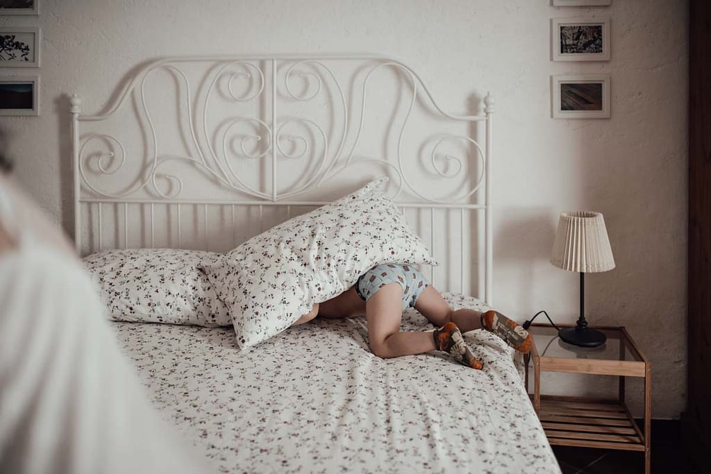 Figlio che si nasconde sotto il cuscino nel letto della location preparazione sposi Magliano Sabina Figlio più piccolo della coppia si nasconde sotto il cuscino nel letto della location per la preparazione sposi a Magliano Sabina, Rieti, durante un servizio fotografico di matrimonio.