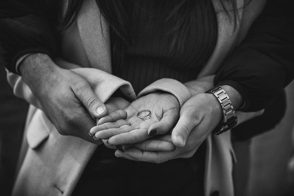 Anello di Fidanzamento al Dito: Coppia felice dopo la Proposta Primo piano delle mani di una coppia unite, con l'anello di fidanzamento al dito. Simbolo di amore dopo la proposta.
