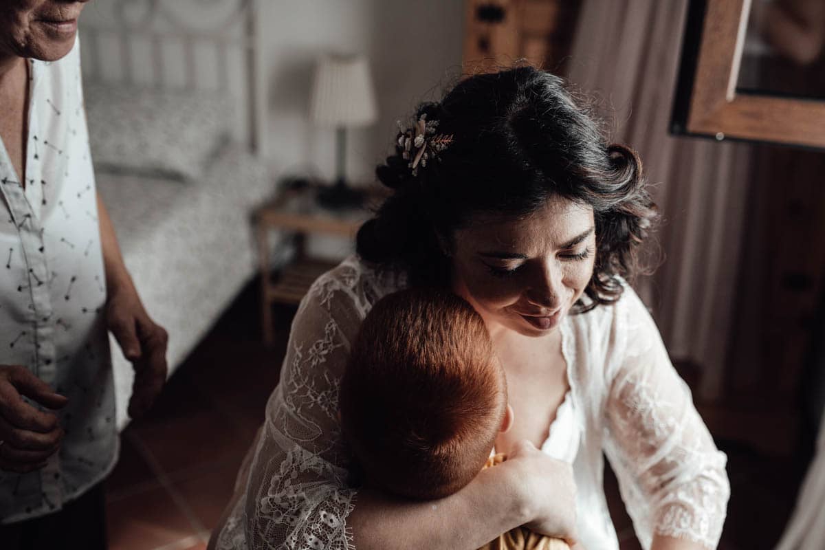 La sposa abbraccia suo figlio durante i preparativi del matrimonio presso una location a Magliano Sabina (Rieti), catturando un momento emozionante di tenerezza e connessione.