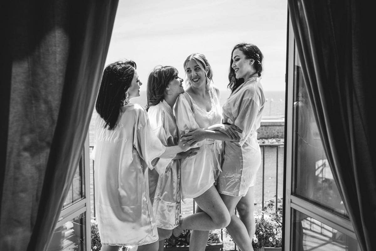 preparazione della sposa con le damigelle su vista mare di Civitavecchia. Fotografo matrimonio Civitavecchia mare: Sposa e damigelle sul balcone con vista mare durante la preparazione.