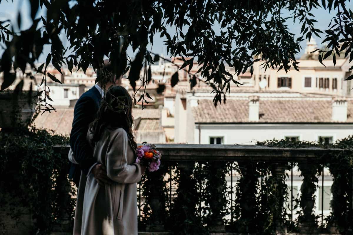 Micro wedding: Abbraccio romantico durante il matrimonio al Piazzale Caffarelli a Roma Fotografia di coppia che si abbraccia durante il loro matrimonio mentre passeggiano nel Piazzale Caffarelli a Roma, catturando un momento di intimità e amore.