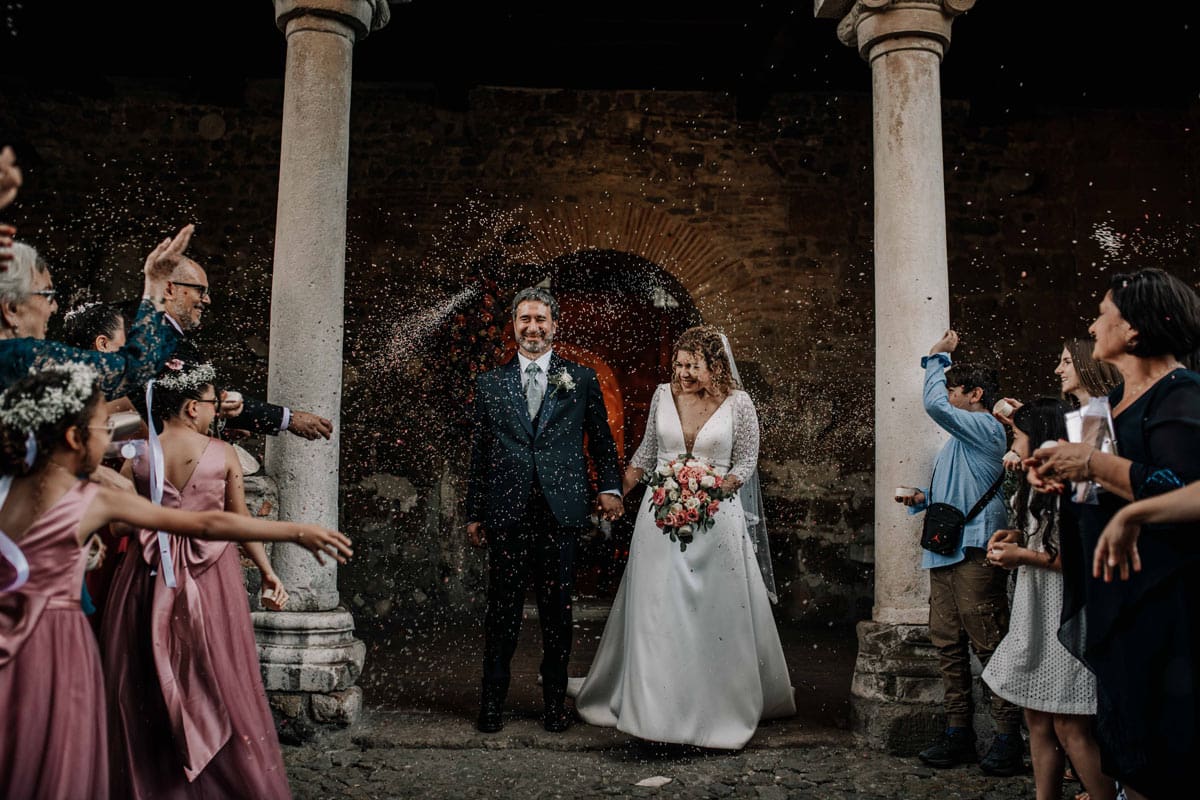 Tradizione e Gioia: Lancio del Riso a San Liberato Gli sposi escono dalla chiesa a Tenuta San Liberato a Bracciano tra un festoso lancio di riso da parte degli invitati.