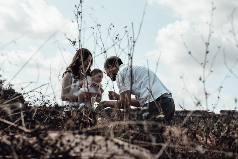 Un Momento di Gioia in Famiglia Mamma che tiene in braccio la figlia mentre il papà la fa giocare al Parco degli Acquedotti, Roma